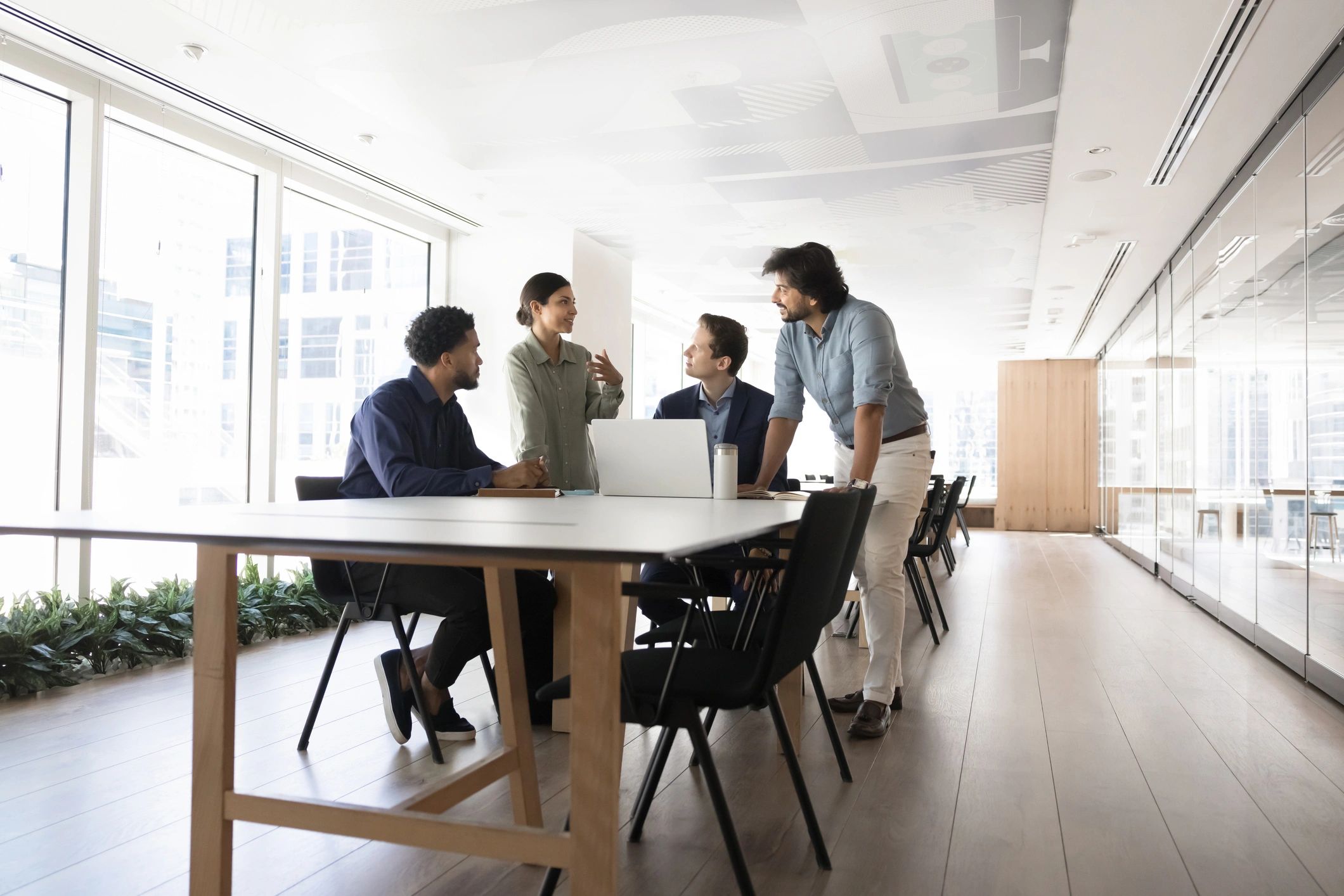 Coworkers discussing strategy around a meeting table with a laptop